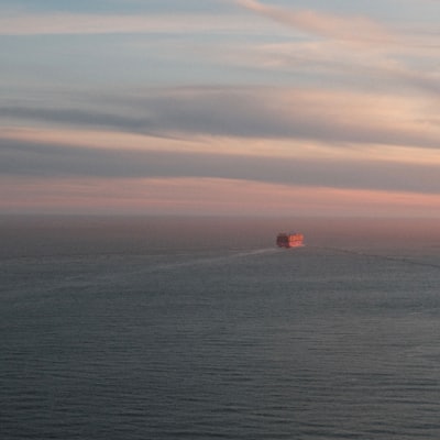 Cargo ship sailing on the ocean under a pastel sky